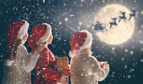 Santa Claus flying in his sleigh against moon sky.