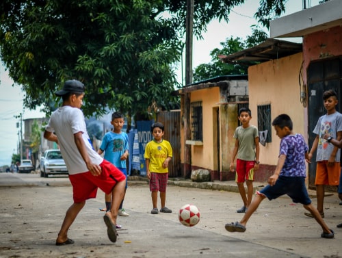 Latin children playing soccer football in streets in Guatemalan village.