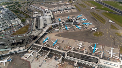 Aerial bird view of Schiphol Amsterdam Airport on a cloudy day. A lot of KLM jets are parked at the gate.