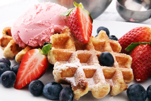 Plate of belgian waffles with strawberry ice cream, and fresh strawberries.