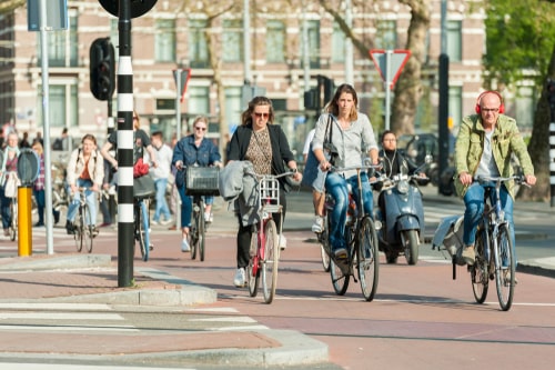 Traffic, cyclists, scooter and pedestrians on a crossroad in Amsterdam in spring.