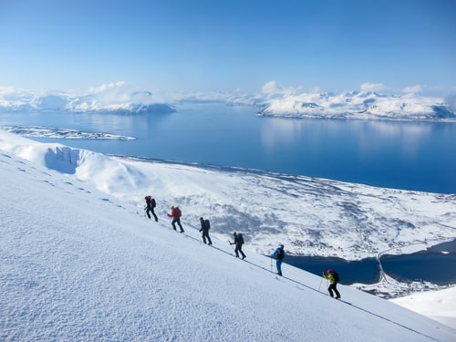 A group of people randonee ski walking high above the fjords. Lyngen Alps, Norway.