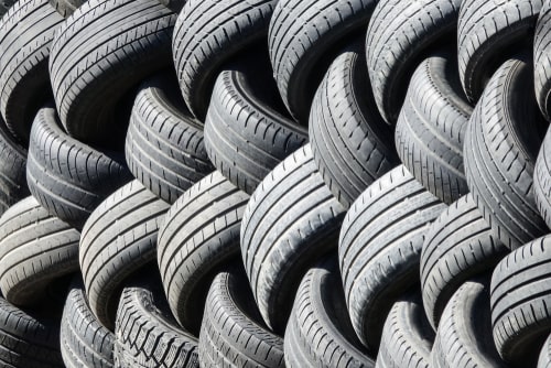 Old used tires that are lined up in a pile.