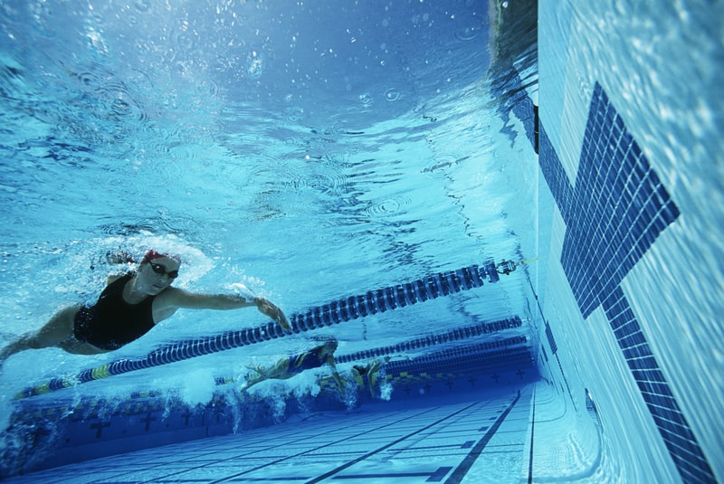 Professional female swimmer about to touch finishing line during a race. facts about Swimming