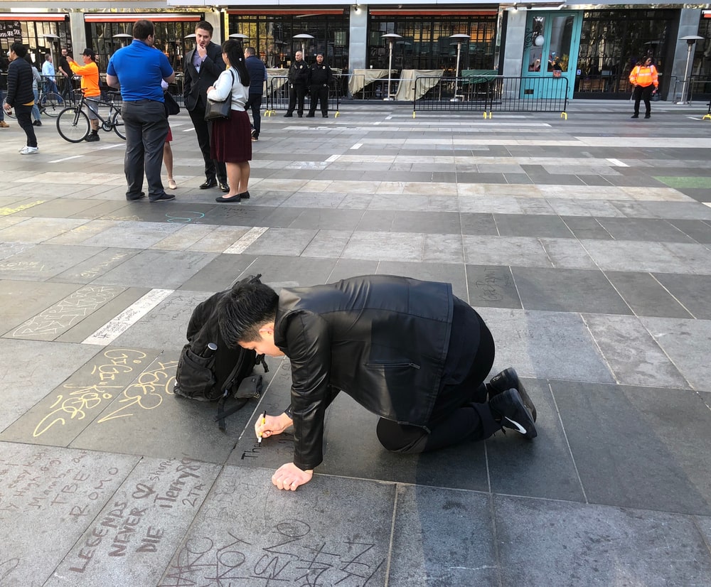 Fan writing a tribute message to sports legend Kobe Bryant outside the Staple's Center in downtown LA.