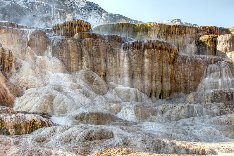 Mammoth Hot Springs are the main attraction of the Mammoth District. These features are quite different from thermal areas elsewhere in the park. Travertine formations grow much more rapidly than sinter formations due to the softer nature of limestone. As hot water rises through limestone, large quantities of rock are dissolved by the hot water, and a white chalky mineral is deposited on the surface.