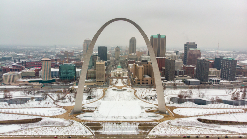 Aerial view of a downtown covered in snow behind Gateway Arch.