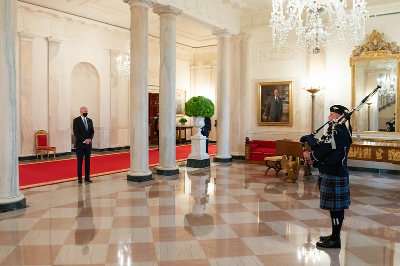 President Joe Biden listens as a member of the U.S. Air Force Band plays the bagpipes in honor of St. PatrickGÇÖs Day on Wednesday, March 17, 2021, in the Grand Foyer of the White House.-min