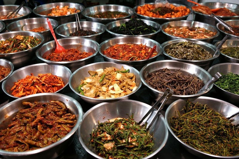 Metal bowls full of various fermented vegetables (kimchi).