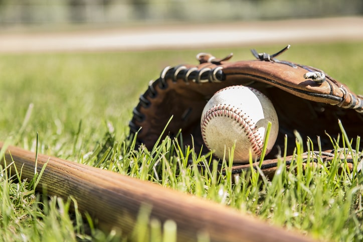 . Wooden bat, glove, and weathered ball lying on baseball field 